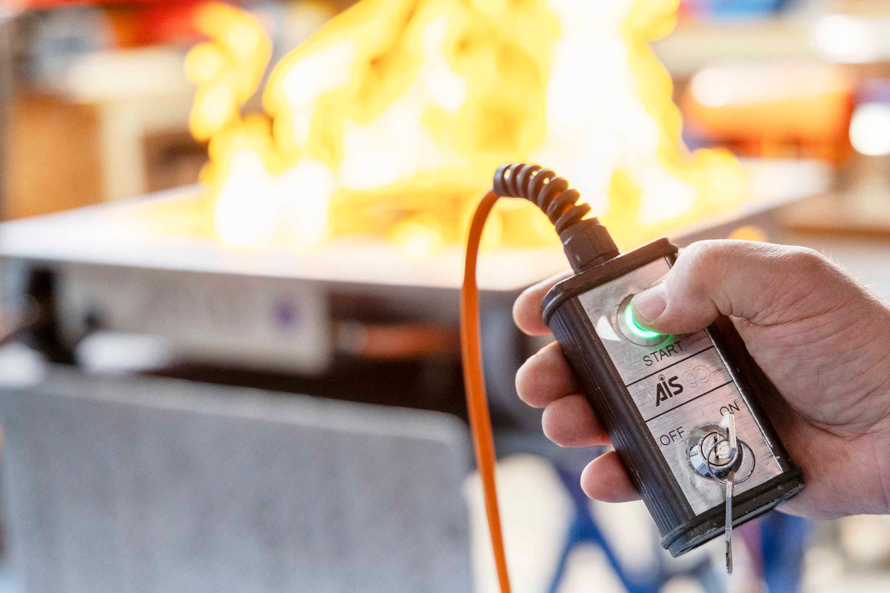 Handfernbedienung eines E 100 Firetrainers wird während Wartung gedrückt, Feuer im Hintergrund