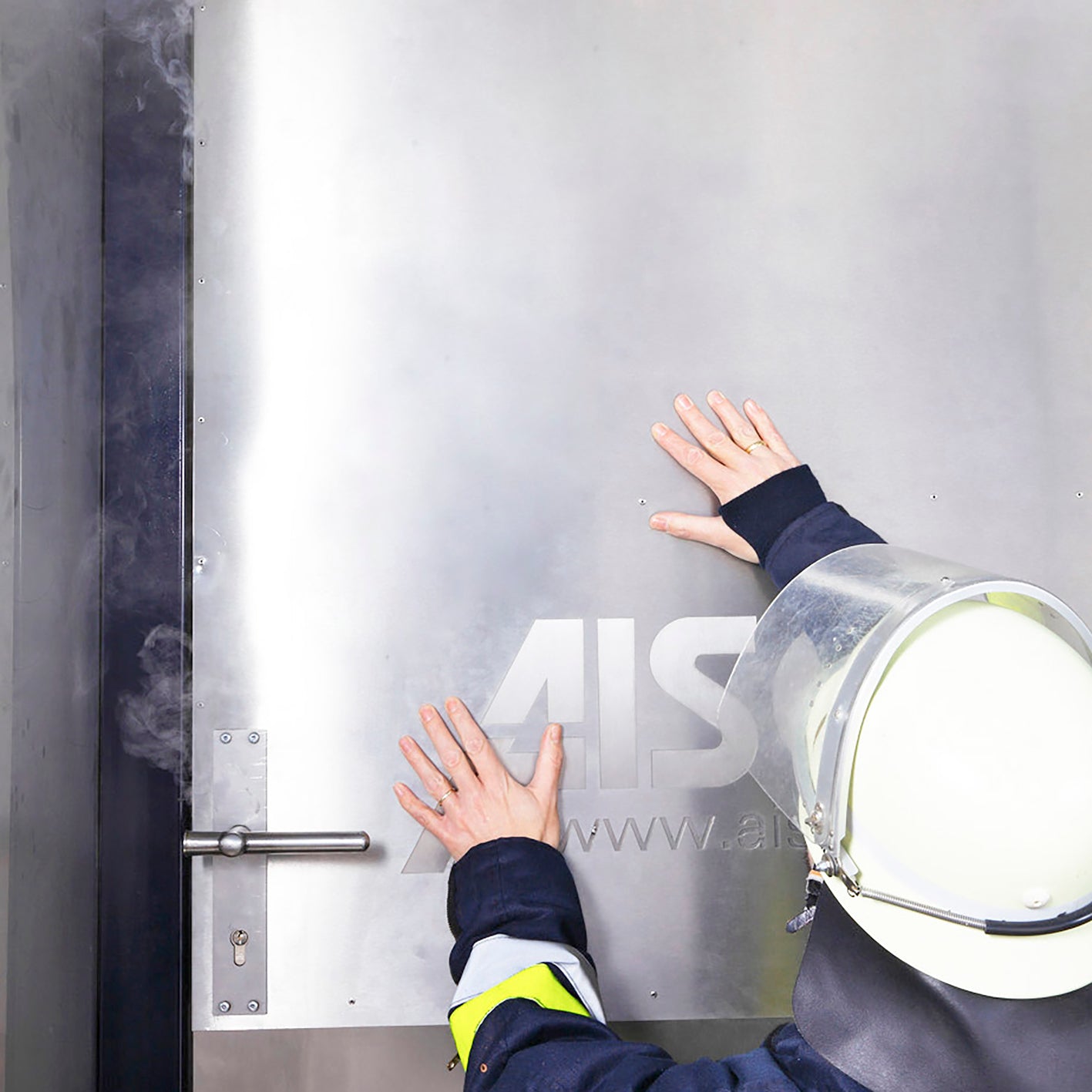 AISCO Heiße Tür, Türblatt wird durch Feuerwehrmann abgetastet und man sieht den Rauchaustritt zwischen Türblatt und Türzarge 