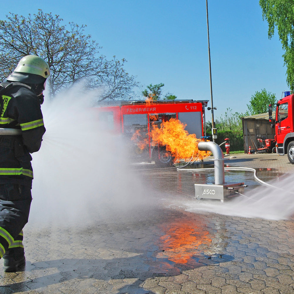 Firefighters perform a hollow jet nozzle training to extinguish the fire while using the AISCO Firetrainer Caddy M with industrial valve. Teamwork in fire protection training with professional equipment