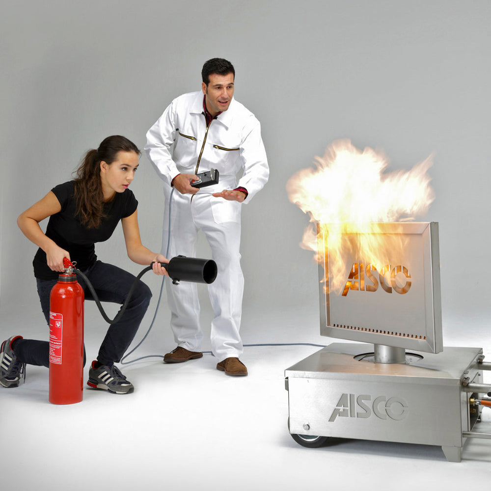 Schüler löscht Feuer am Caddy mit TFT-L-Monitoraufsatz mit CO2-Löscher, Trainer erklärt Löschtechnik